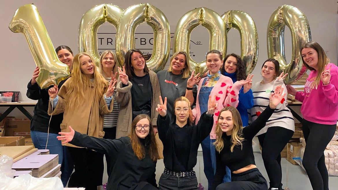 TreatBox UK team. The Team at Treatbox behind lots or large, filled Royal Mail bags with the warehouse in the background.