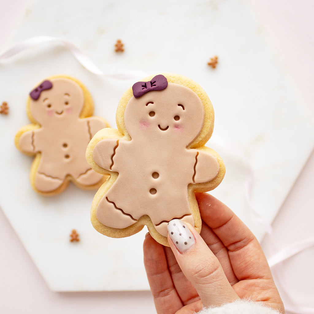 decorated gingerbread person cookie in the foreground, with another similar cookie blurred in the background