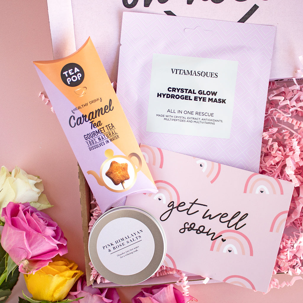 Get well soon box in pinks and purples with an eye mask, bath salts, caramel tea and get well soon postcard