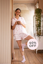 Woman in pink pajama set holding a mug in a room with a '40% OFF' label.