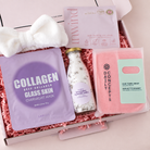 A curated skincare gift box filled with pink shredded paper, containing a white bow headband, a lavender Laapos Collagen Deep Collagen Glass Skin Overnight Mask packet, a bottle of lavender Epsom bath salts, a pink Concepts by Dain Concept Hair Towel Wrap, and an Inwind Self-Healing eye mask.