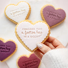 Heart-shaped shortbread cookiess decorated with icing and the phrase 'CONSIDER THIS a festive hug IN A BISCUIT', 
