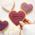 Heart-shaped shortbread cookiess decorated with icing and the phrase 'CONSIDER THIS a festive hug IN A BISCUIT', 