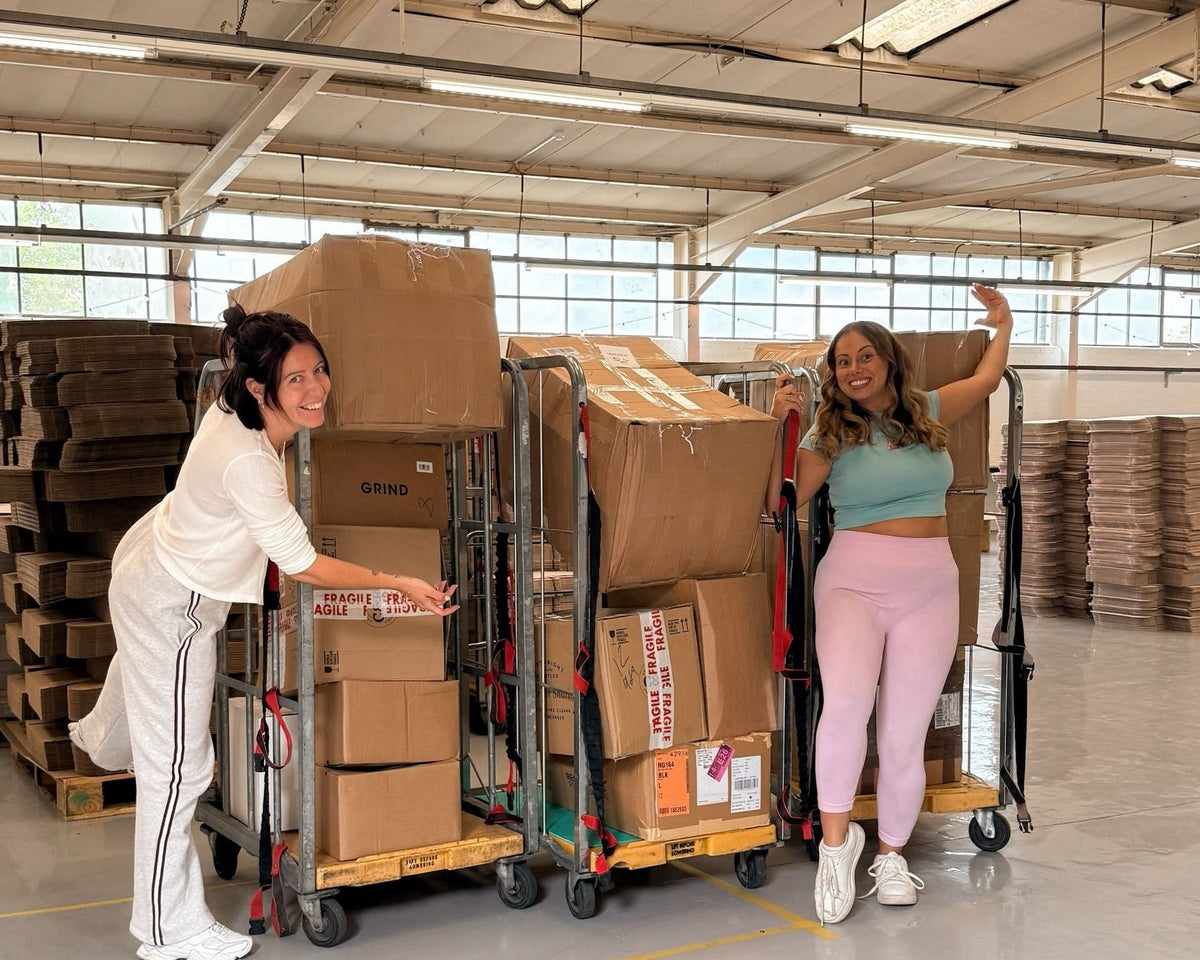 Two women standing in a warehouse with stacked cardboard boxes on carts, with a text overlay that reads 'Father's Day = SAVED'.