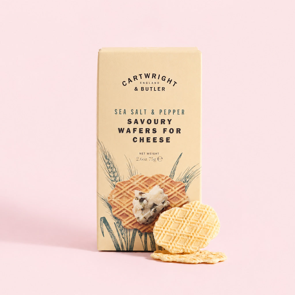 A beige box of Cartwright & Butler Sea Salt & Pepper Savoury Wafers for Cheese, shown on a solid light pink background with two wafers in front.